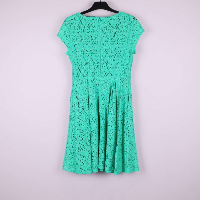 Grön spetsklänning med rund hals och korta ärmar hängande på galge, sedd bakifrån