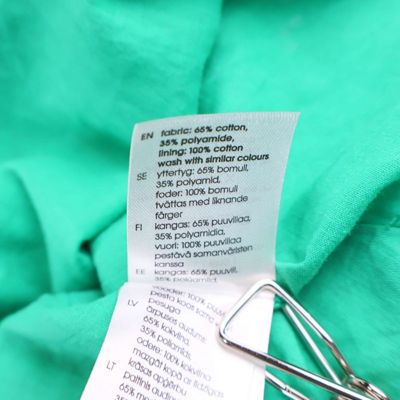 Tvättrådsetikett som visar materialinformation på klänning