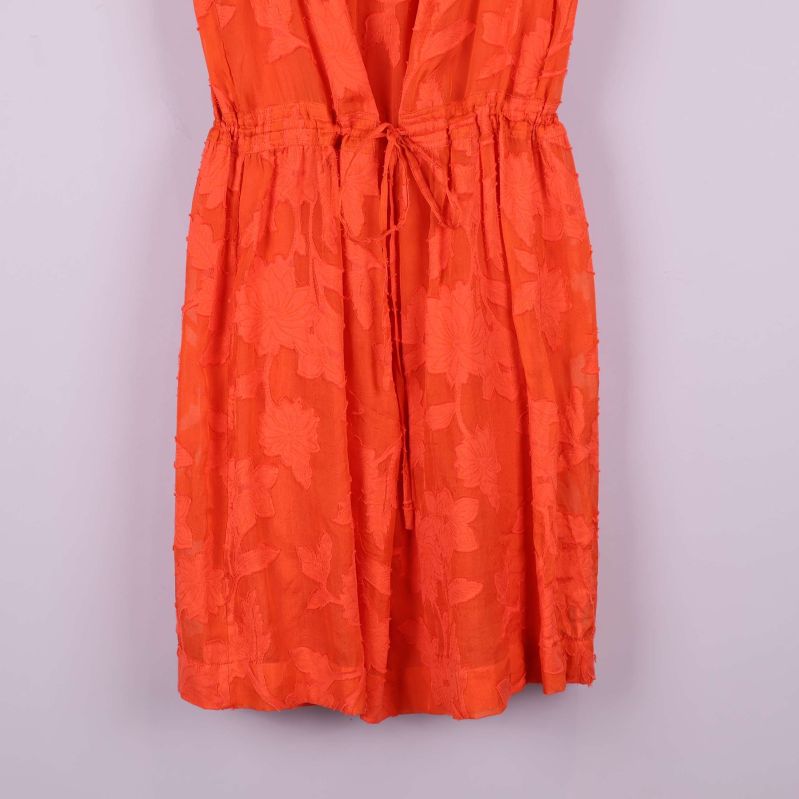 Nedre del av orange klänning med strukturmönster och knytband