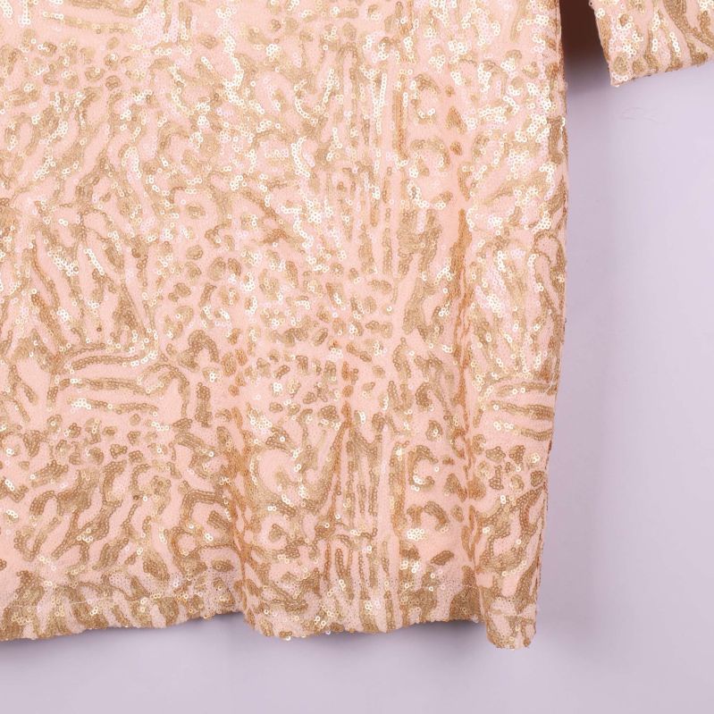 Närbild nedre delen av beige paljettklänning med mönster