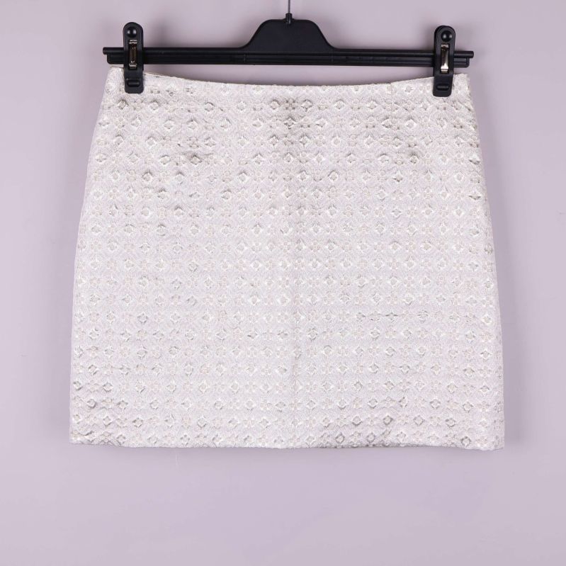 Kort kjol i ljust tyg med strukturmönster framifrån