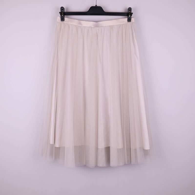 Ljus tyllkjol upphängd mot enfärgad bakgrund framifrån