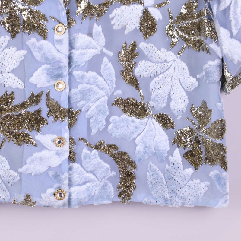 Detaljbild på kavajens nederkant med guldiga knappar och glitter