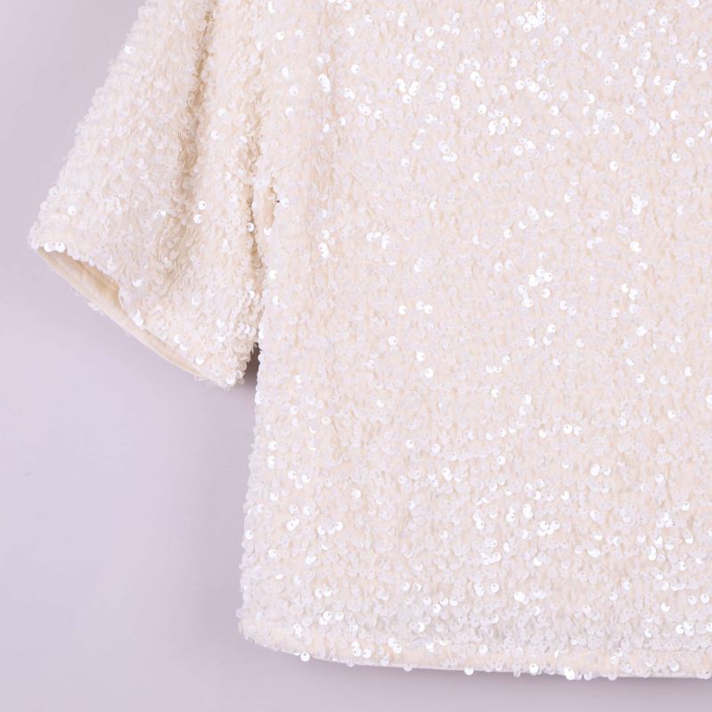 Närbild på nedre delen av paljettoppen och ärm