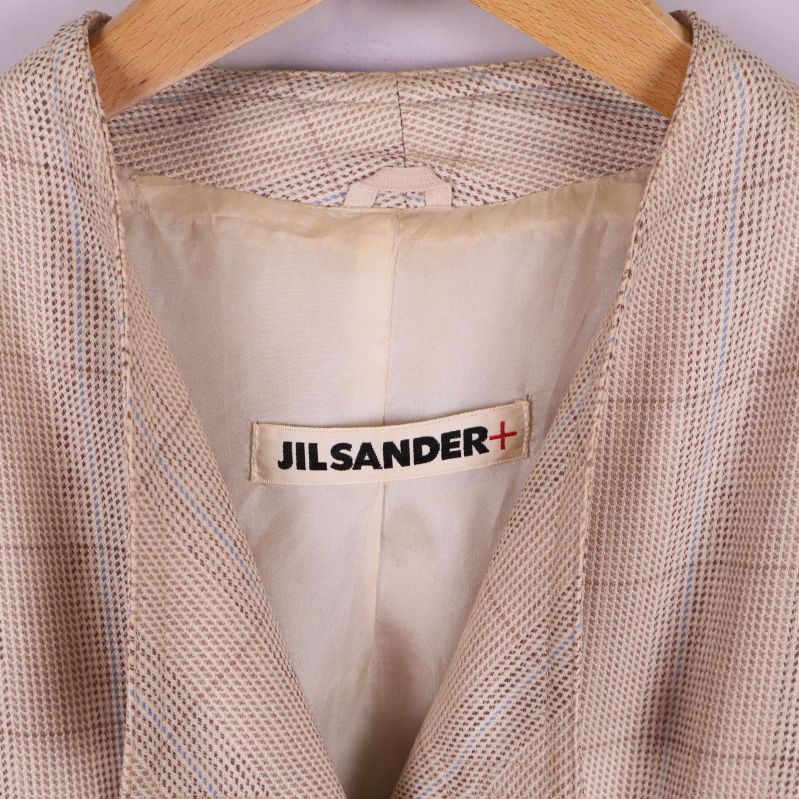 Närbild Jil Sander+ logotyp i kavajens nackparti