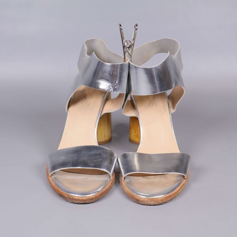 Framifrån vy på silverfärgade sandaler med bred klack