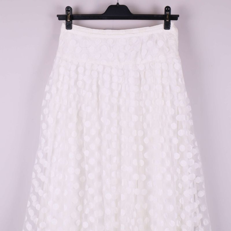 Övre delen av vit kjol med tydligt prickigt mönster