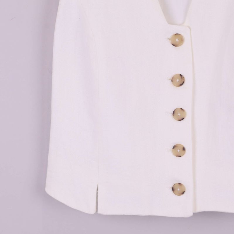 Närbild på nedre delen av västen och knapprad