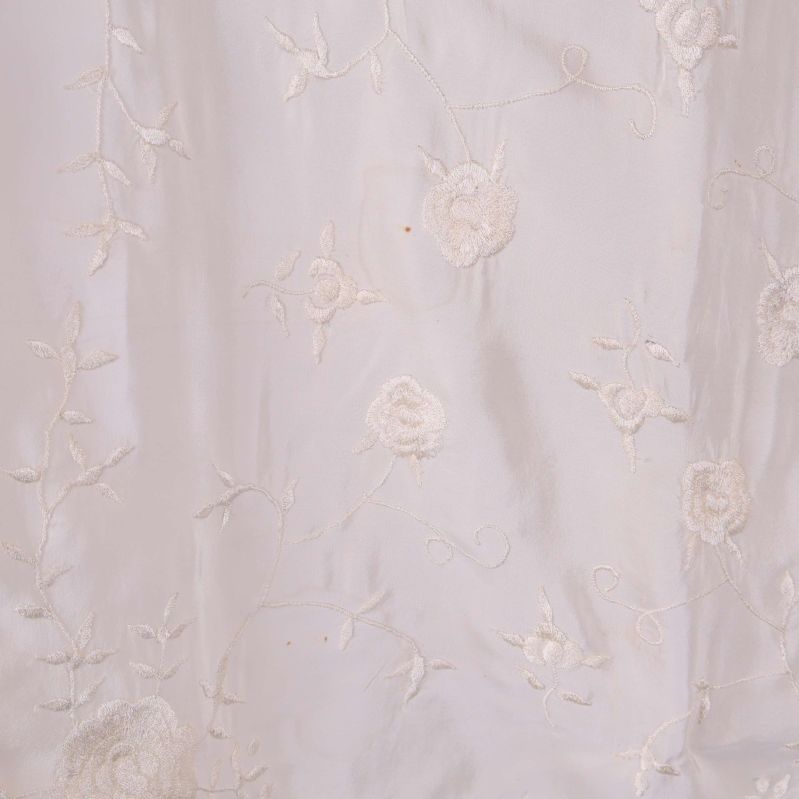 Närbild på broderade blommor i vitt tyg