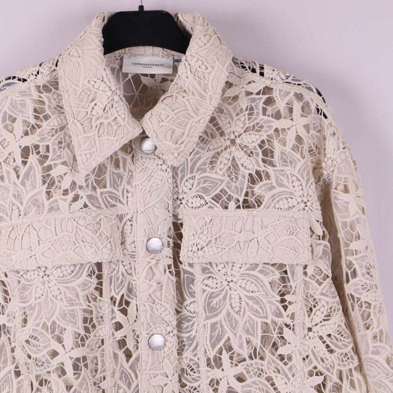 Närbild på krage och fickdetalj på spetsjacka