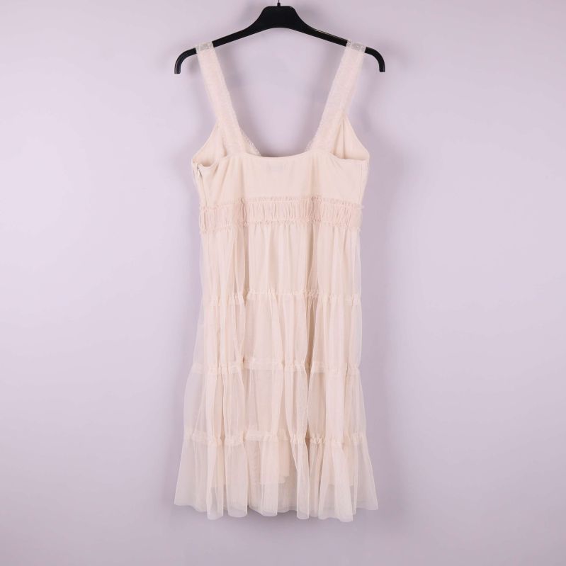 Ljus volangklänning på galge fotograferad bakifrån