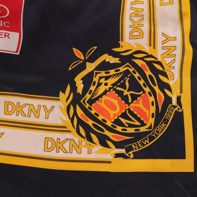 Närbild på emblem och bård i DKNY-scarf