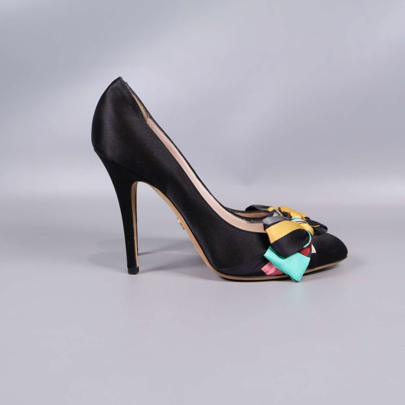 Högklackad pumps sedd från sidan, svart satin och rosett