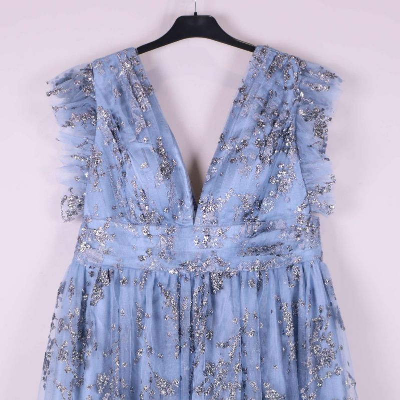 Närbild av djup v-ringning och volang på axlarna