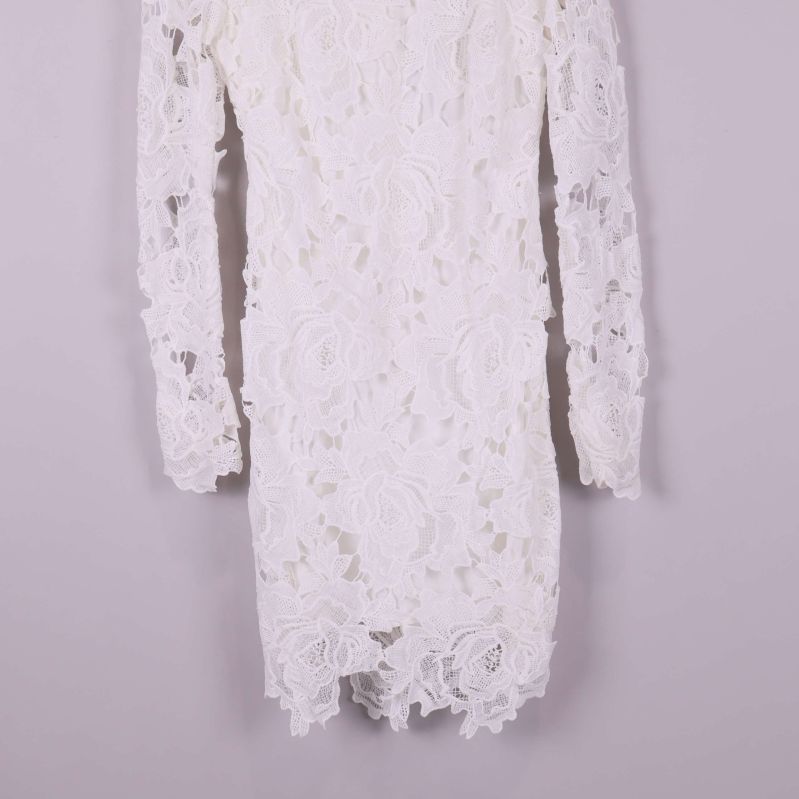 Närbild på underdelen av vit spetsklänning
