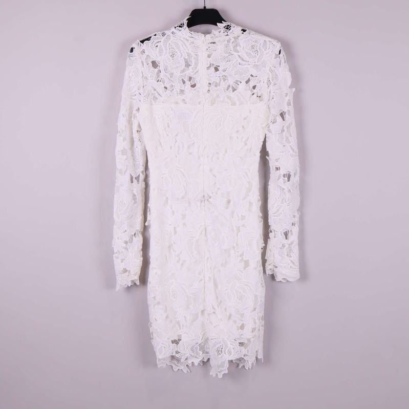 Vit spetsklänning med lång ärm bakifrån mot ljus bakgrund