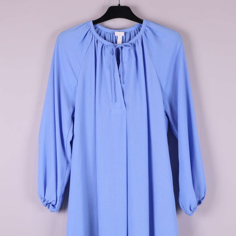 Övre del av blå klänning med ärmar och struktur