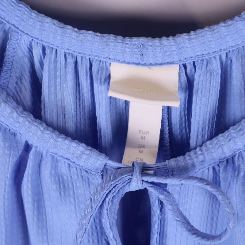 Närbild på halsringning och knytband på klänningen