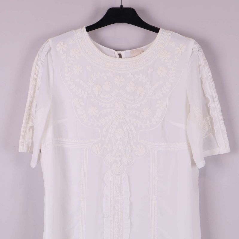 Övre framdel av klänning med spetsmönster och detaljer