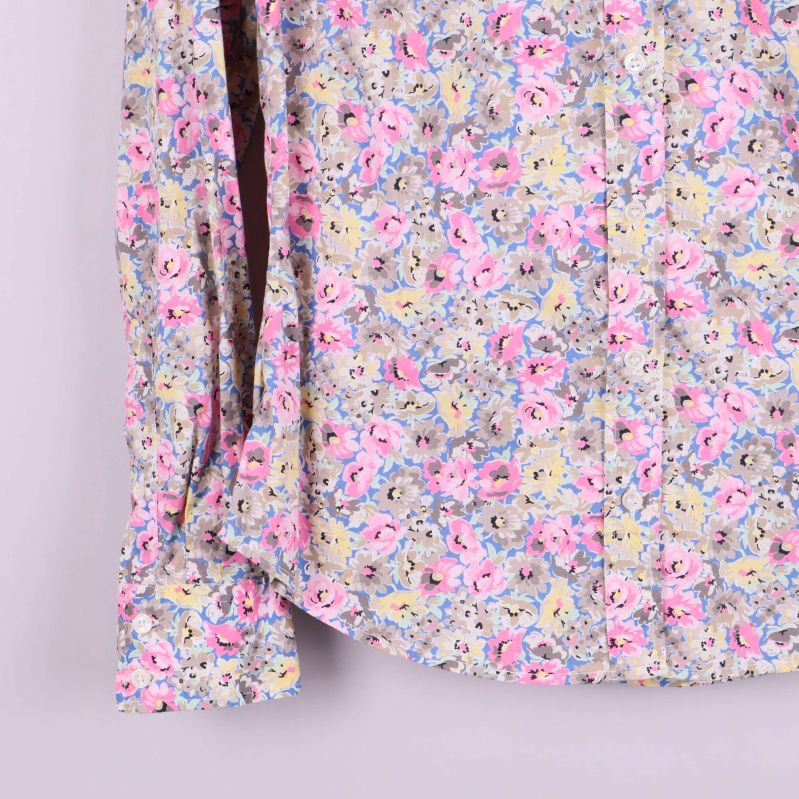 Detalj på skjortans ärm och knappslejf med blommigt mönster