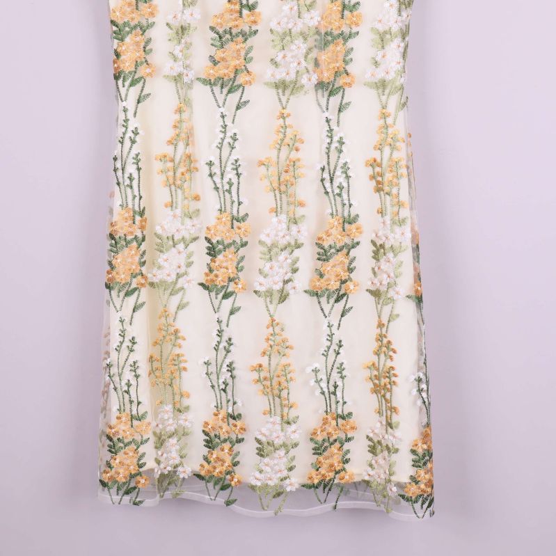 Nederkant av klänning i vitt med blombroderier