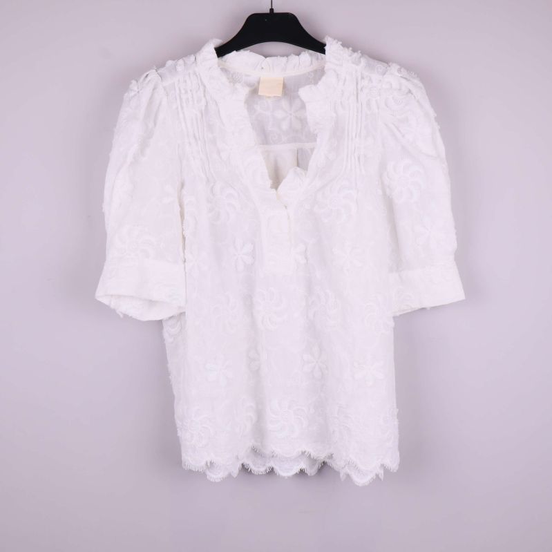 Vit blus med broderade blommor framifrån