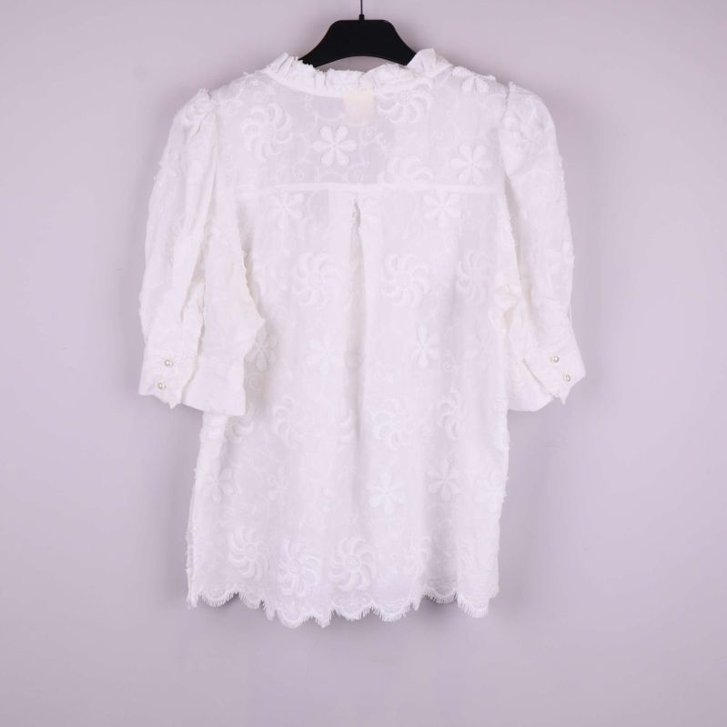 Vit blus med broderade blommor bakifrån