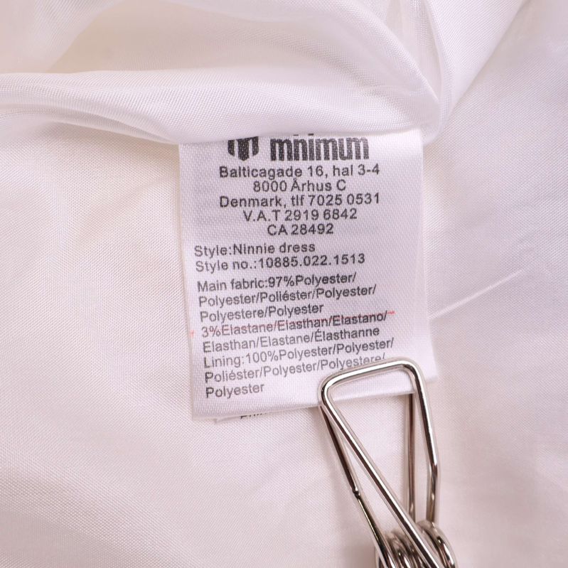 Tvättlapp med materialinformation och tvättråd inuti klänningen