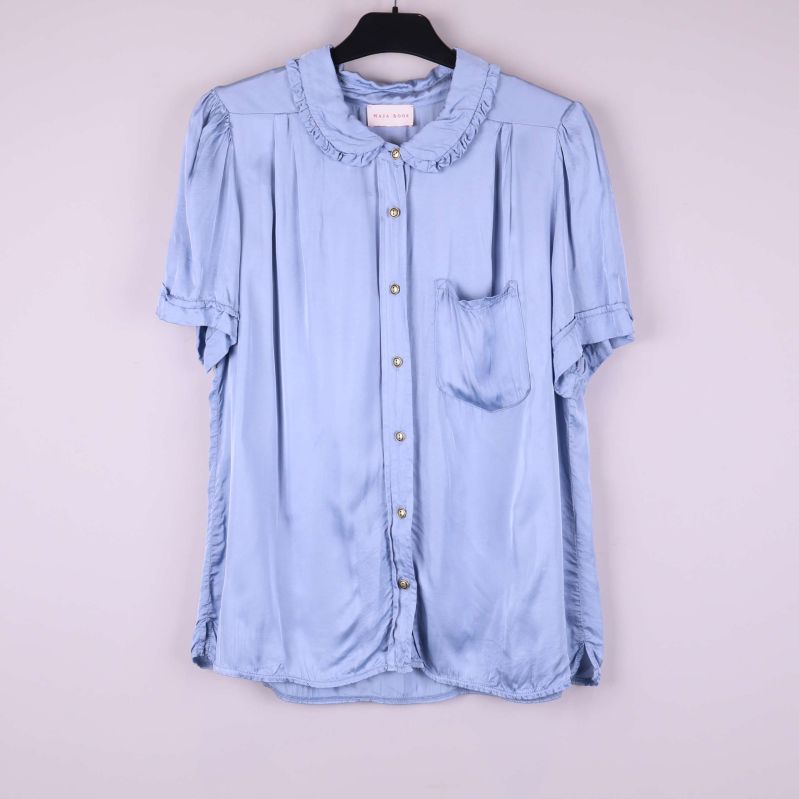 Ljusblå volangblus med kort ärm hängande på galge