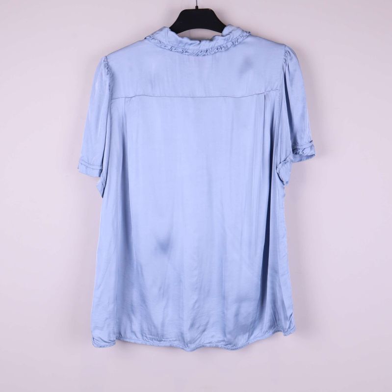 Baksida av ljusblå blus med kort ärm och volangkrage
