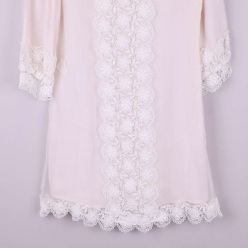 Närbild på klänningens spetsdetaljer vid nederkant och ärmslut