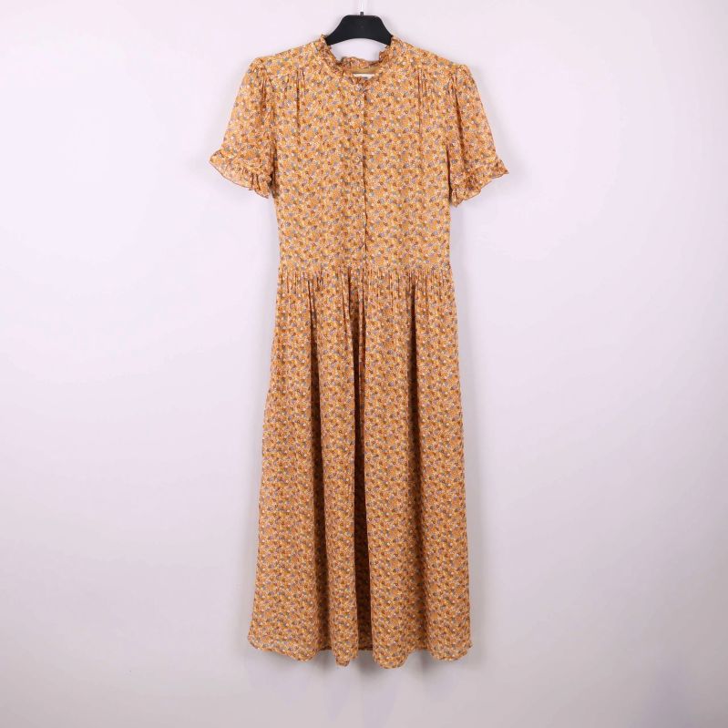 Lång blommig klänning med volanger på galge mot ljus bakgrund