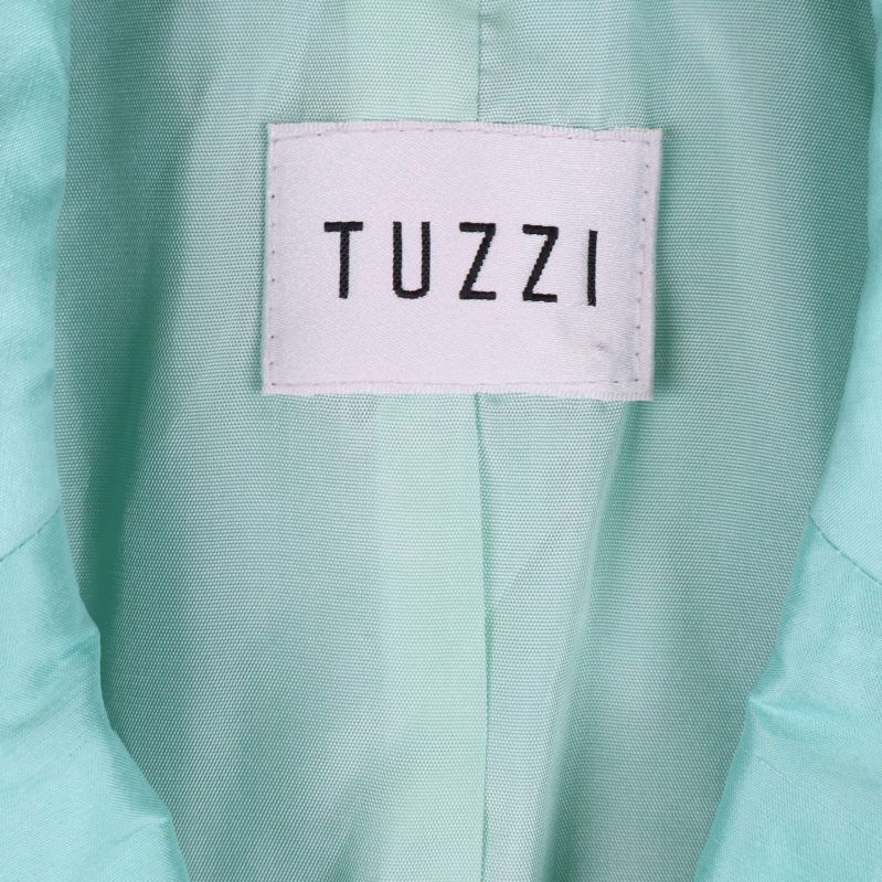 Närbild på Tuzzi etikett i ljusblå blazer