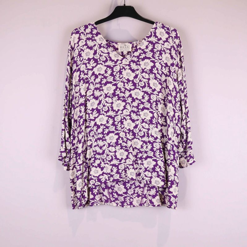 Lila blus med vitt blommönster framifrån på galge