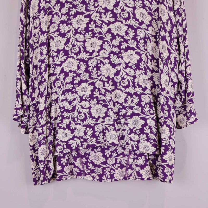 Nedre del av blus med lila och vitt blommönster i fokus