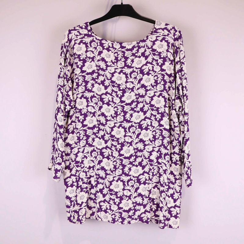 Baksida av lila blus med vitt blommönster på galge