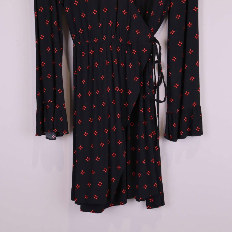 Närbild på kjoldel och volangkant på svart mönstrad klänning