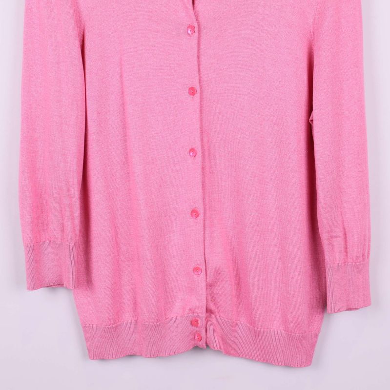 Närbild på nedre delen av rosa cardigan och knäppning