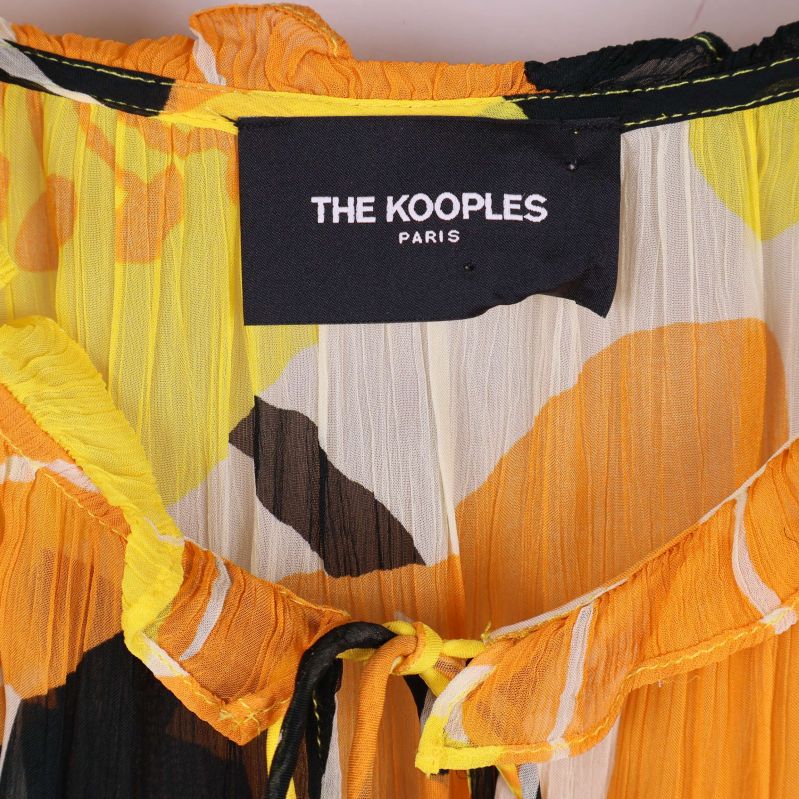 Fokuserad detaljbild på The Kooples etikett på blus
