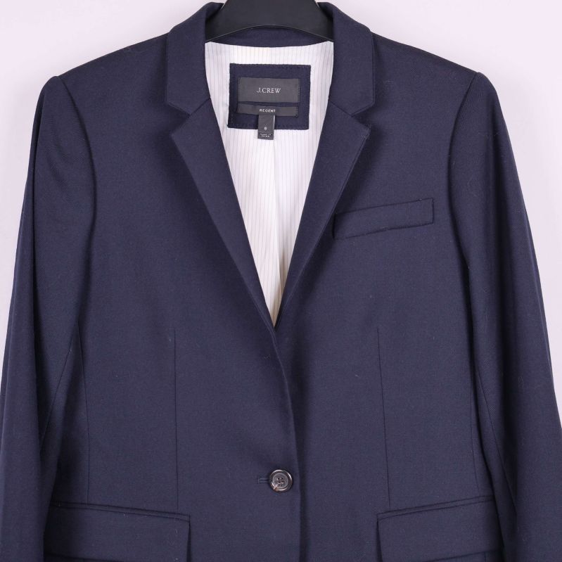 Närbild på bröstficka och knäppning på mörkblå blazer