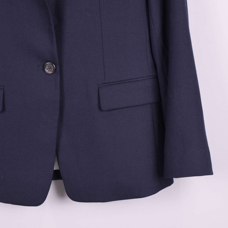 Detalj närbild på knapp och fickor nedtill av blazer