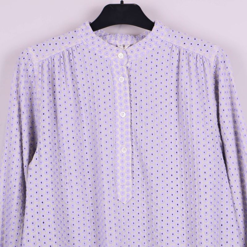 Närbild på blusens knappar och broderidetaljer framtill