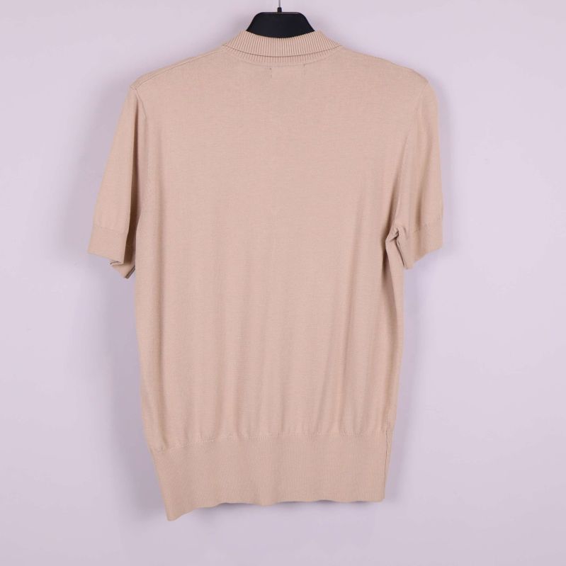 Beige kortärmad pikétröja bakifrån på galge