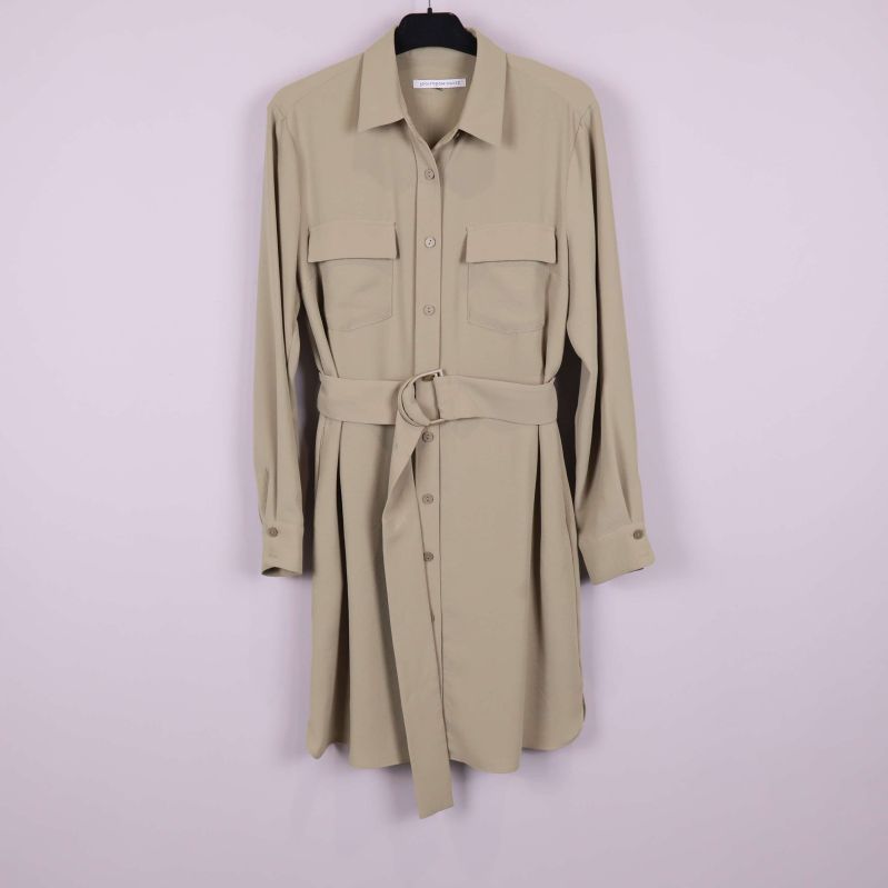 Beige skjortklänning med lång ärm och bälte hängande mot ljus bakgrund