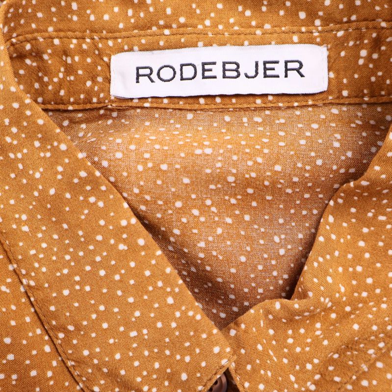 Närbild på Rodebjer-märket i blusens halsringning