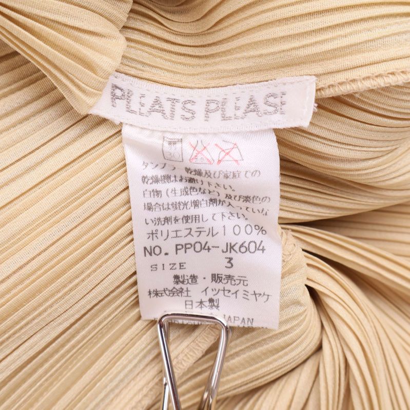 Närbild på Pleats Please-materialetikett med japansk och engelsk text