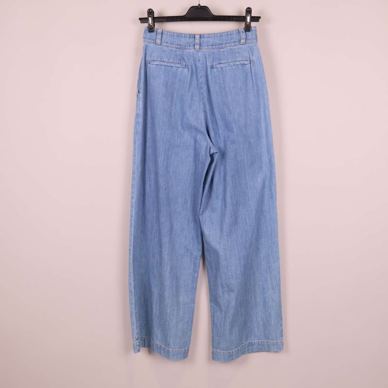 Baksida av ljusblå jeans upphängda på galge