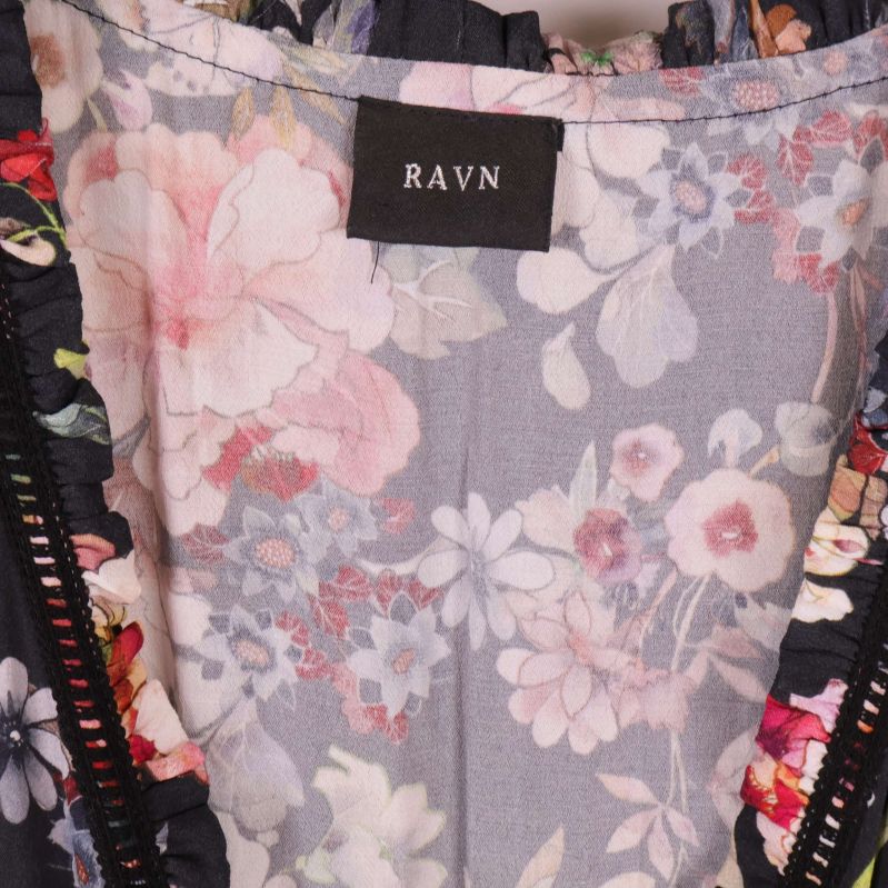 Närbild på klänningens märkning RAVN och blommigt tyg