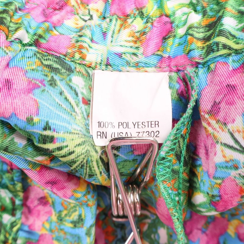 Materiallapp med texten 100% polyester i blommiga byxor