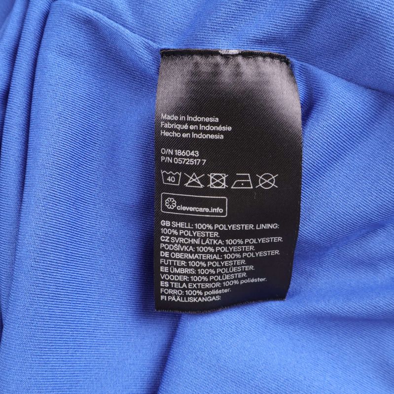 Materialetikett som visar yttertyg 100% polyester